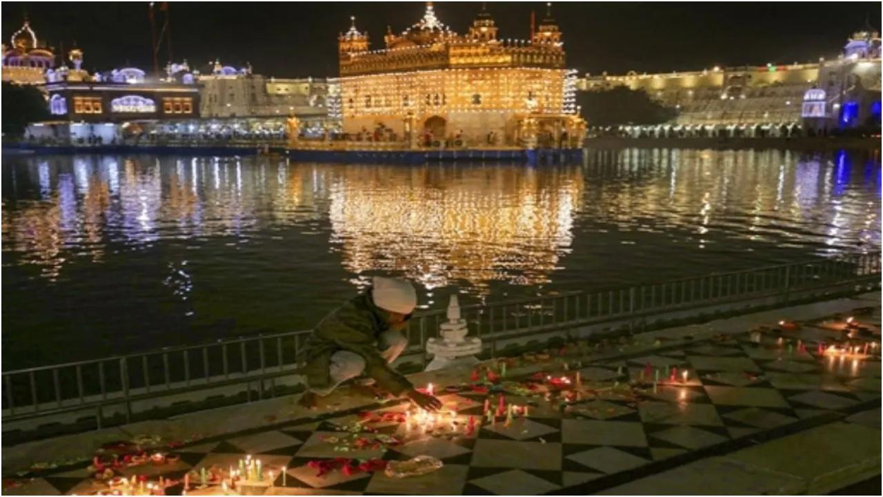 अमृतसर: सोमवार, 27 नवंबर, 2023 को अमृतसर में गुरु नानक जयंती पर स्वर्ण मंदिर में एक भक्त मोमबत्ती जलाता है. पीटीआई फोटो