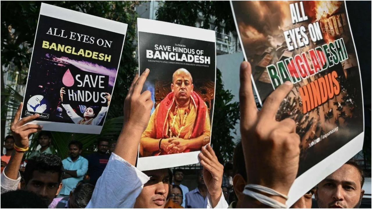 हिंदू भिक्षु चिन्मय कृष्णदास ब्रह्मचारी की गिरफ्तारी के बाद बांग्लादेश में जारी अशांति के बीच 2 दिसंबर, 2024 को मुंबई में बांग्लादेश उच्चायोग के बाहर विरोध प्रदर्शन के दौरान भक्त और अंतर्राष्ट्रीय कृष्ण भावनामृत संघ (इस्कॉन) के सदस्य पोस्टर पकड़े हुए हैं. (तस्वीर/एएफपी)