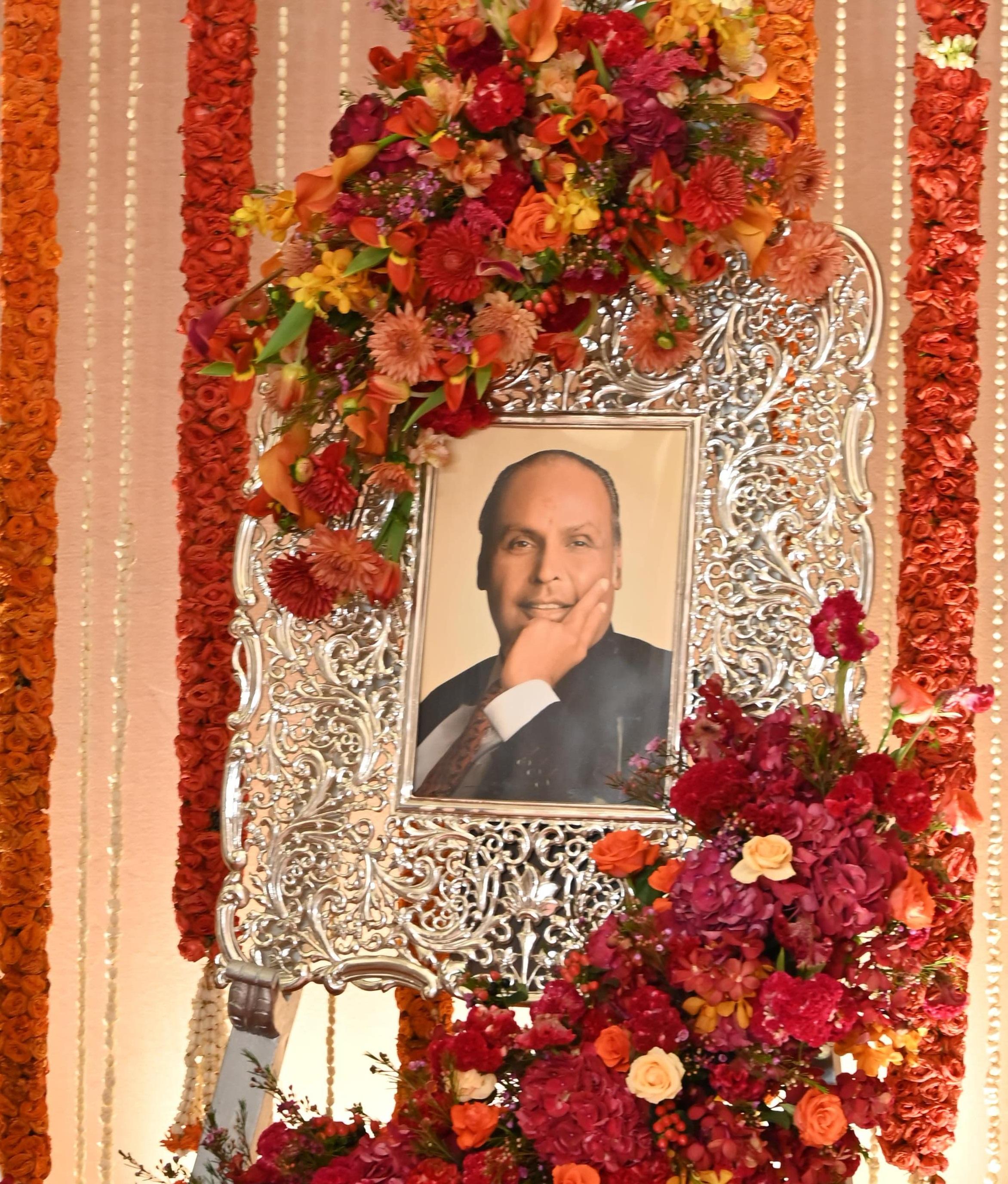 अनंत राधिका की शादी के लिए तैयार किए रेड कारपेट पर अंबानी परिवार के मुखिया और मुकेश अंबानी के पिता धीरू भाई अंबानी की तस्वीर भी लगाई गई.