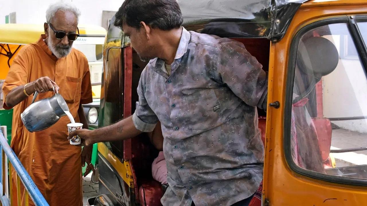 गुरुवार को सूरत में जैन समुदाय का एक सदस्य एक ऑटो रिक्शा चालक को गर्मी से राहत पाने के लिए `छाछ` वितरित करता है.