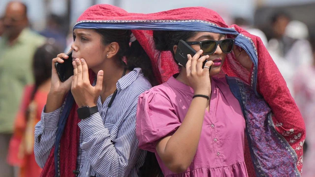 महिलाएं गुरुवार, 23 मई, 2024 को मुंबई में एक गर्मी के दिन तेज धूप से बचने के लिए अपने सिर को ढकती हैं. (PTI फोटो/शशांक पराड़े)
