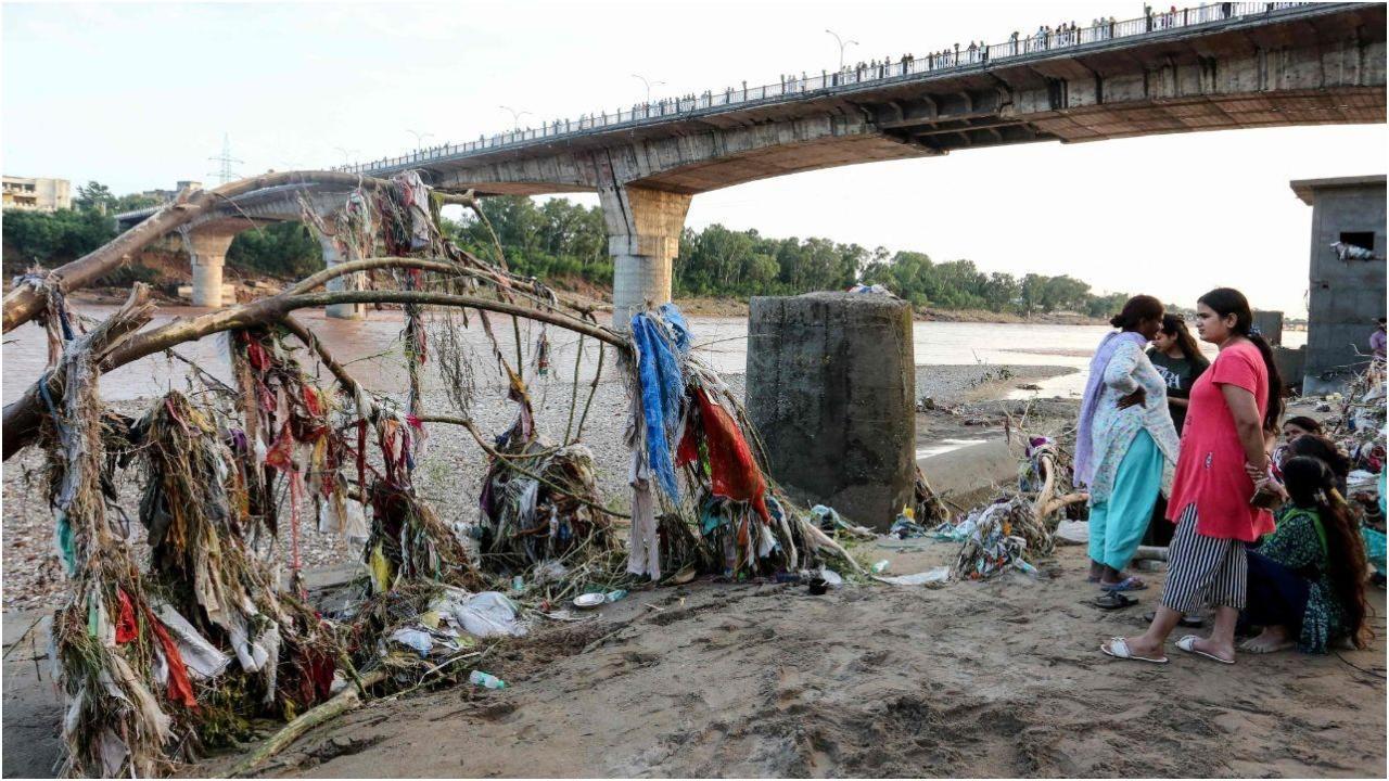 जम्मू में भारी बारिश के बाद आई बाढ़ के बाद उफनती तवी नदी के किनारे अपने घरों के पास बिखरे मलबे का निरीक्षण करते निवासी. (तस्वीर/पीटीआई)
