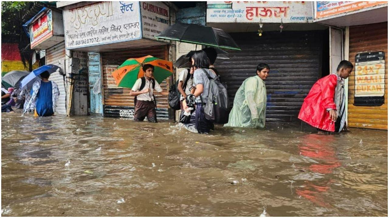सायन के गांधी मार्केट में जांघों तक पानी भर जाने से आवाजाही बाधित हो रही है और स्कूली बच्चे जलमग्न सड़कों से होकर गुज़र रहे हैं. तस्वीर/ ऐश्वर्या अय्यर
