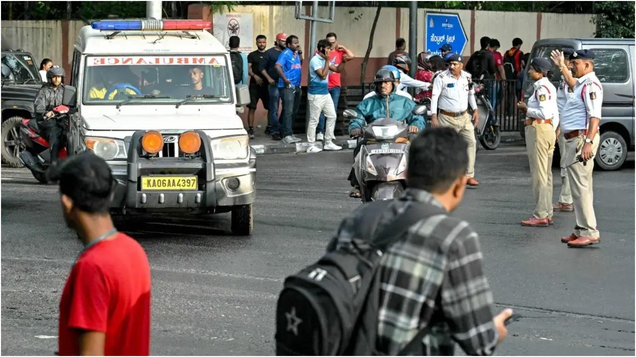 बेंगलुरु के एम. चिन्नास्वामी स्टेडियम के पास ट्रैफिक पुलिस के जवान एम्बुलेंस को रास्ता देते हुए. तस्वीर/एएफपी