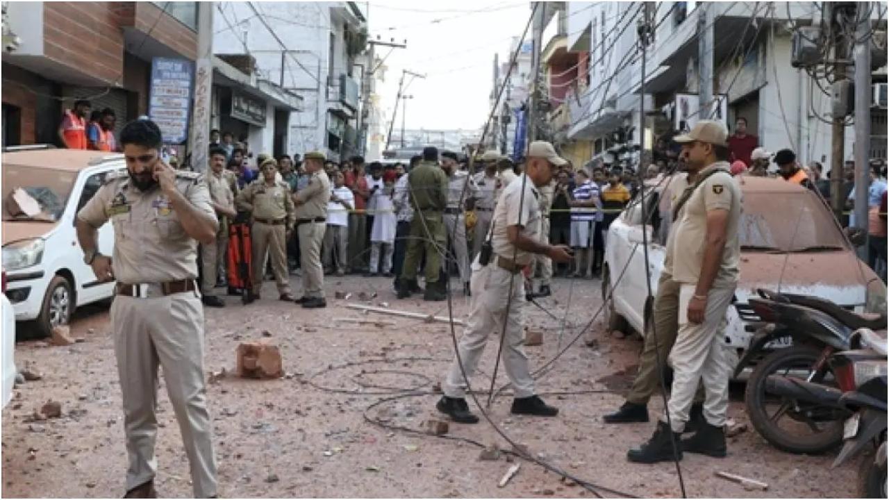 जम्मू में पाकिस्तान की ओर से हुए हमले में क्षतिग्रस्त वाहनों के पास सुरक्षाकर्मी और नागरिक एकत्रित हुए. (तस्वीर/पीटीआई)
